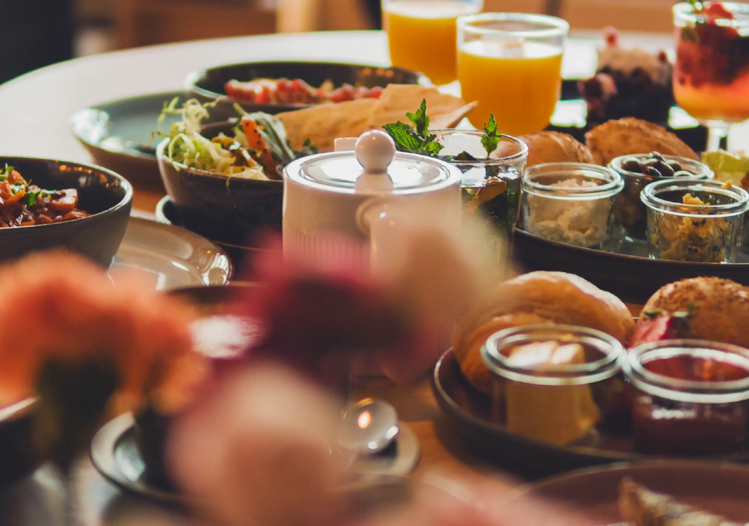 Stimmungsvolle Tischszene mit Brötchen, Dips, Salaten und Saft.