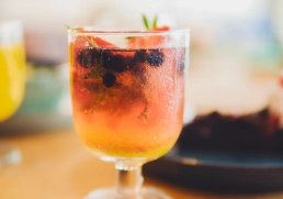 Makroaufnahme eines Getränks mit Beeren, Minze und Eiswürfeln.