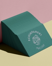 Stapel dunkelgrüner Visitenkarten mit rundem Schimpanski-Logo und Handschrift „Café & Deli“.