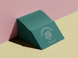 Stapel dunkelgrüner Visitenkarten mit rundem Schimpanski-Logo und Handschrift „Café & Deli“.