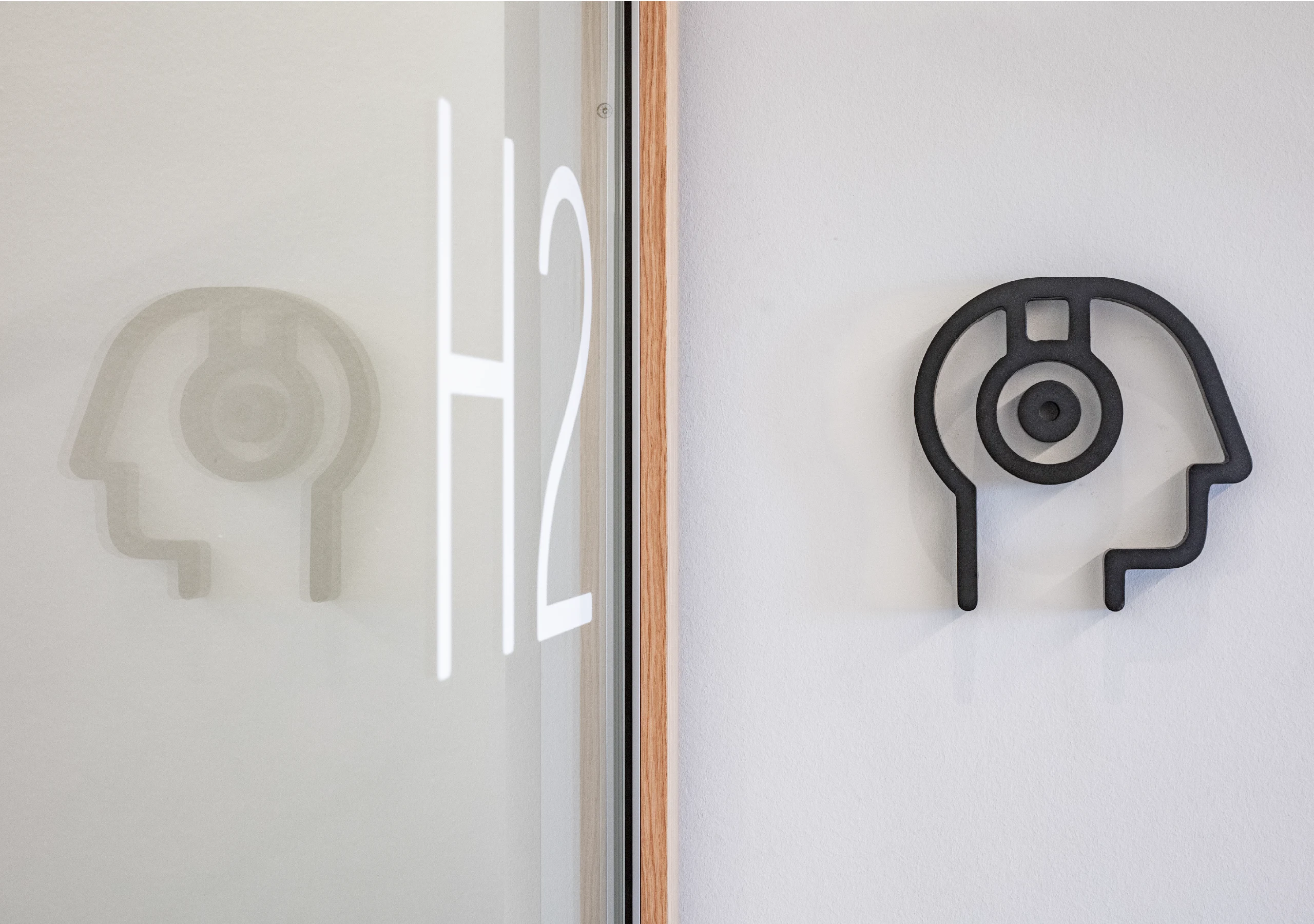 Schwarzes Kopf-Icon mit Sensorik neben Glastür H2.